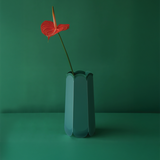 POTR Letterbox Vase with a red flower against a green background, showcasing its origami-inspired design.